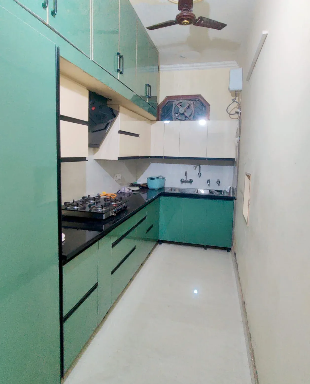 Modular kitchen with green cabinets, black countertop and white wall units